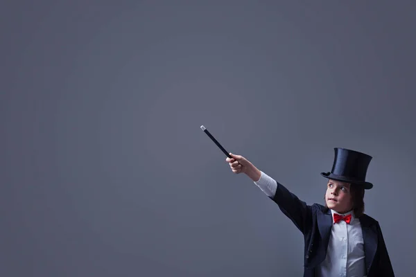Magician boy with hardhat pointing to copy space with magic wand — Stock Photo, Image