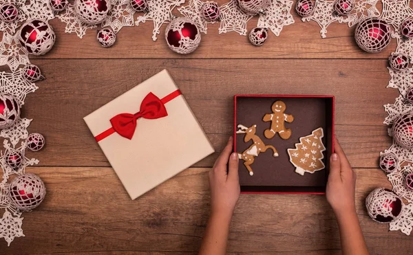 Crianças mãos abrindo presente de Natal com biscoitos de gengibre — Fotografia de Stock