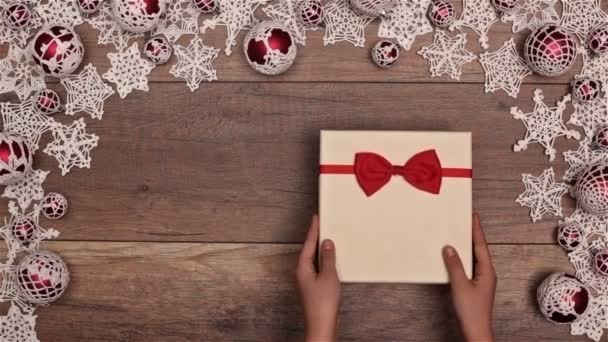 クリスマス プレゼント木製のテーブル上の季節のフレーム内部を開く手のトップ ビュー — ストック動画