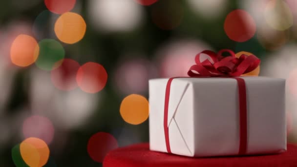 クリスマス プレゼントにクリスマス ライト背景をぼかした写真に赤いリボンのクローズ アップ — ストック動画