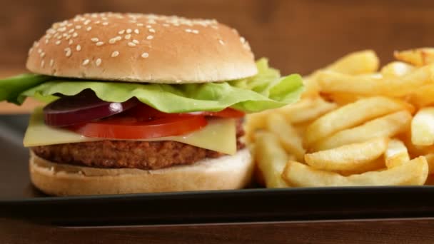 おいしいハンバーガーとフライド ポテト黒プレート — ストック動画