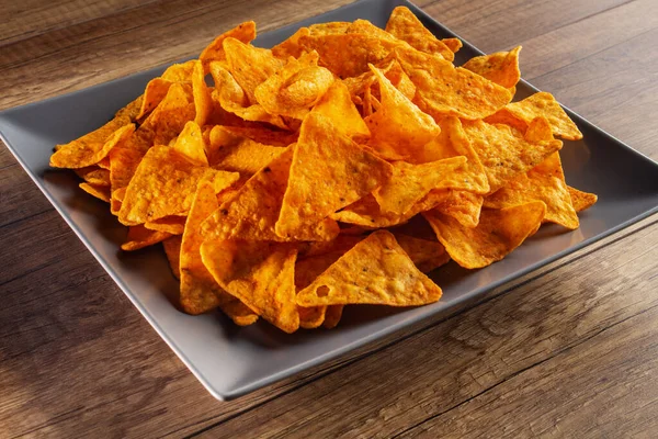 Delicious tortilla chips on a rectangular plate - close up of appetizing spicy corn flour triangles