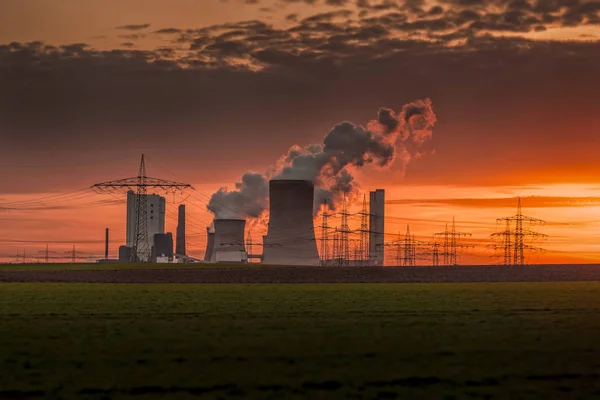 Power station and transmission towers lit by a notewothy sunset.