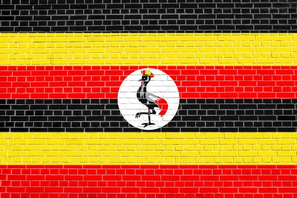 Ugandská vlajka na pozadí textury cihlové zdi — Stock fotografie