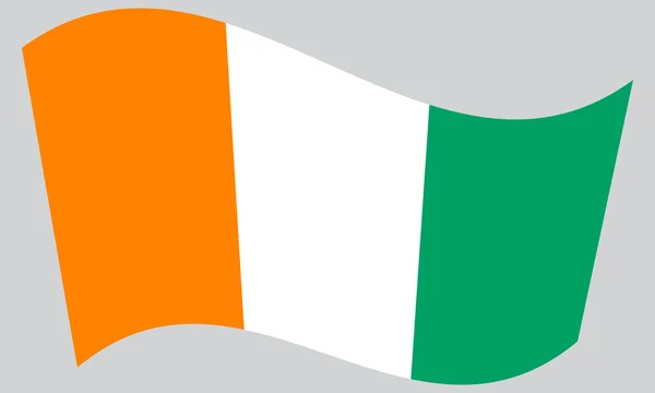Flag of Ivory Coast waving on gray background — Stock Vector