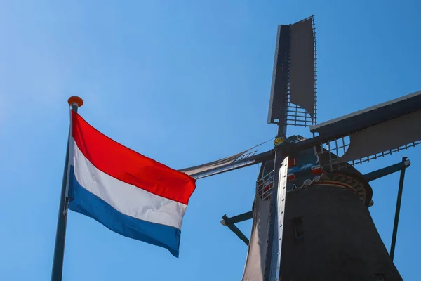 Знаменитая голландская ветряная мельница и флаг Нидерландов — стоковое фото