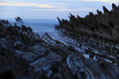 Itzurun plajında gün batımında kayalar üzerinde dalgalar
