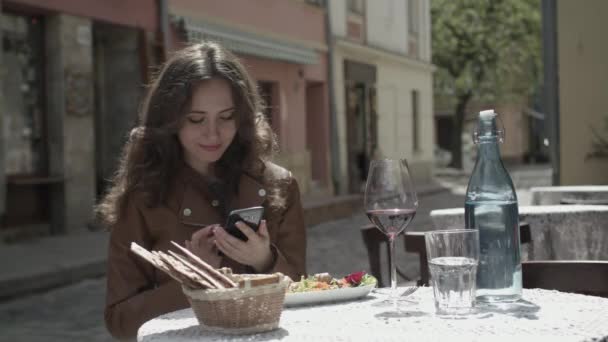 Молодая девушка использует свой смартфон в кафе — стоковое видео