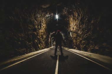 ışıklı bir tünel girişinde duran adam