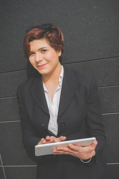 Young authentic business woman with tablet pc smiling in the financial district for business trip — Stock Photo, Image