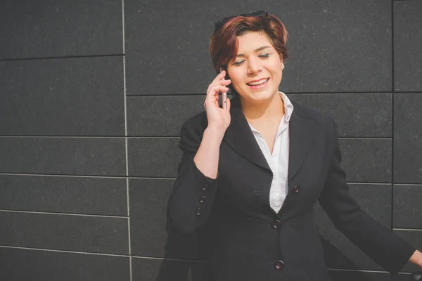 Молодая деловая женщина разговаривает со своим смартфоном в финансовом районе для деловой поездки — стоковое фото
