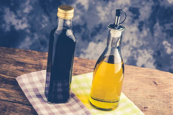 Bottiglia di olio d'oliva e aceto balsamico su tavola rustica — Foto Stock