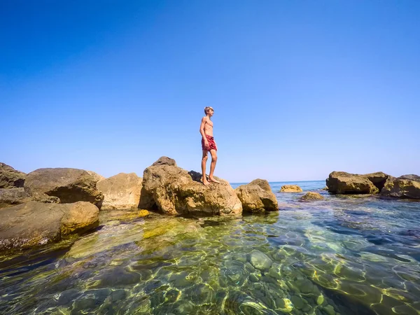 Teenager standing on the rocks at seaside - summertime — Stock Photo, Image