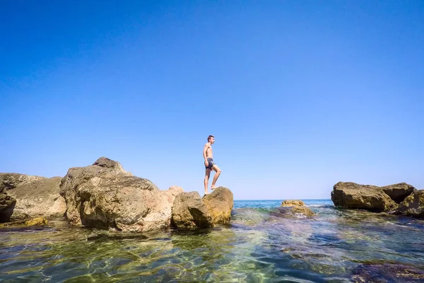 Teenager standing on the rocks at seaside - summertime — Stock Photo, Image