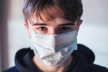 Koruyucu maskeli genç çocuk - enfeksiyon korkusu kavramı - evde karantina - evde kal
