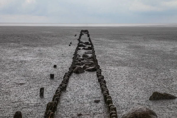 Vecchio molo rotto sulla spiaggia di pietra del Mar Baltico — Foto Stock