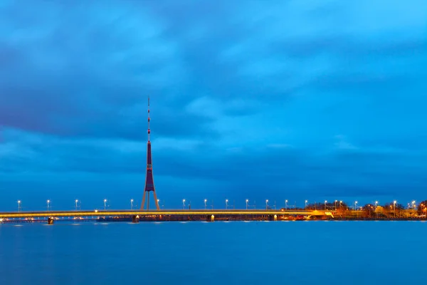 Vista da torre de TV Riga e ponte iluminada à noite, Letónia — Fotografia de Stock