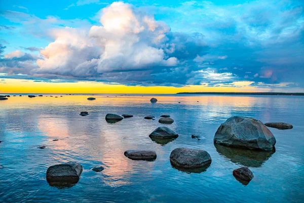 Hell gefärbte Meer Sonnenuntergang mit Steinen entlang der Küste — Stockfoto
