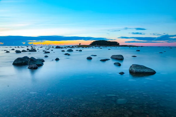 Gekleurde zonsondergang over zee met stenen langs de kust. Lange blootstelling — Stockfoto