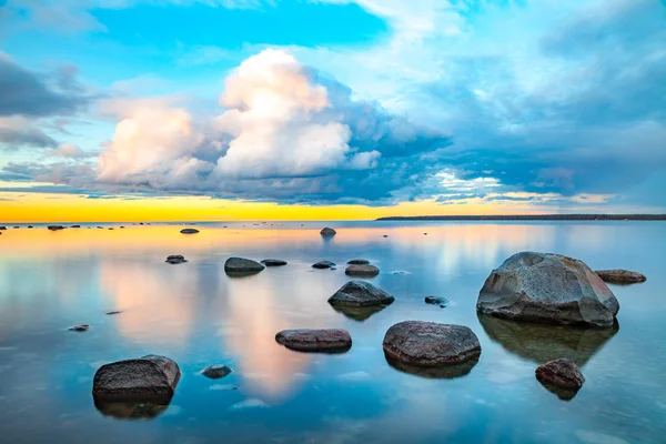 Яркий морской закат с камнями вдоль побережья — стоковое фото