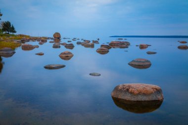 Su, uzun pozlama içinde taş olan güneş battıktan sonra Baltık sahil