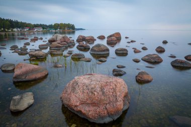 Su, uzun pozlama içinde taş olan güneş battıktan sonra Baltık sahil