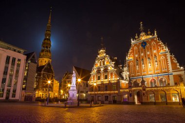 Riga, Letonya - 25 Aralık 2015. City Hall Square siyah nokta evi ile aydınlatılmış ve Aziz Peter Kilisesi eski kentte