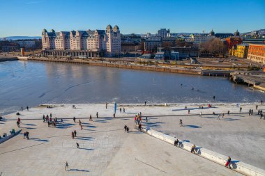 Oslo, Norveç - 27 Şubat 2016: Bjorvika Körfezi ve dolgu. İnsanlar Opera Evi çevresinde yürüyor.