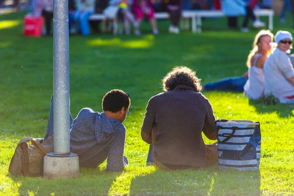 İki kıvırcık adam Park güneşli yaz günü, çimenlerin üzerinde rahatlatıcı arkadan görünüm