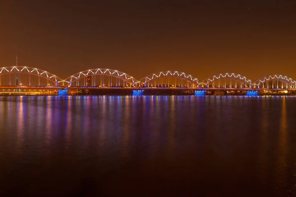 Ponte ferroviária iluminada à noite em Riga, Letónia — Fotografia de Stock