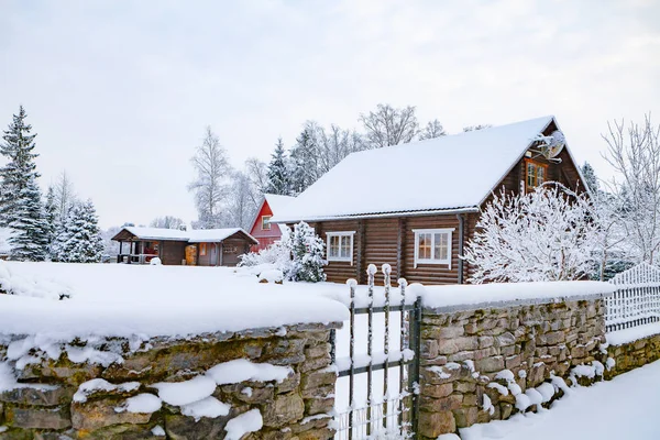 Recinzione in pietra coperta di neve e cottage sullo sfondo Immagine Stock