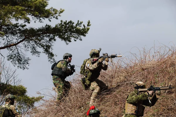 Humala、エストニア - 2016 年 4 月 9 日: 武器迷彩の兵士の Goroup は新しい位置を得ています。軍の戦術的な airsoft のゲーム. — ストック写真