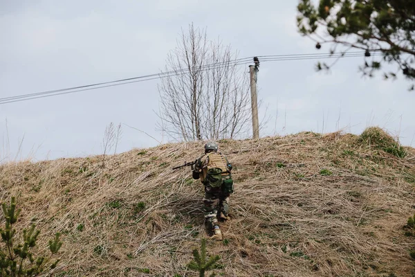 HUMALA, ESTONIA - 09 ABR 2016: Soldado en camuflaje con arma protege su posición. Militar táctica airsoft juego . — Foto de Stock