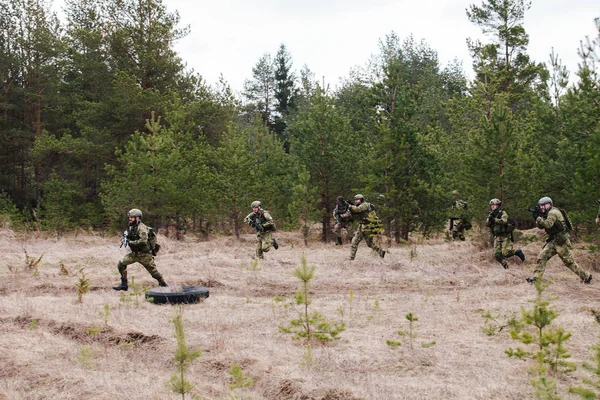 HUMALA, ESTONIA - 09 ABR 2016: Goroup de soldado en camuflaje con arma está consiguiendo una nueva posición. Militar táctica airsoft juego . — Foto de Stock