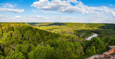 Güzel gökyüzü ve bulutlar yeşil orman, Güneş tarafından kaplı tepeler üzerinde. Turaida Kalesi: Gauja Nehri, Letonya yakınında vurdu.