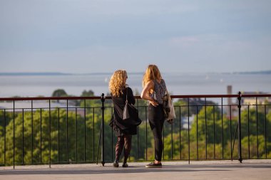 Tallinn, Estonya - 02 Haziran 2016. İki genç kadın gözlem güverteden şehir manzarasının tadını çıkarın. Güneşli yaz gün.