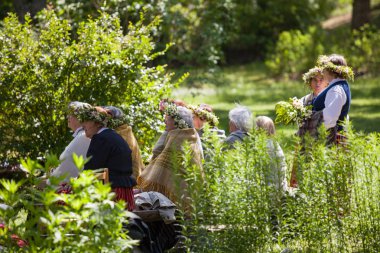 Riga, Letonya - 12 Haziran 2016: Letonyalılar siitting ve ulusal kostümleri folklor şarkıları söyleyerek dinleme. Letonca Etnografya Müzesi.