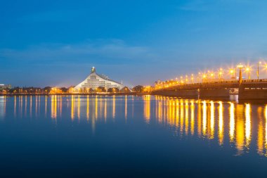 Letonya Milli Kütüphanesi ve taş Riga'da Daugava Nehri üzerinde köprü. Gece ışıklı sahne.