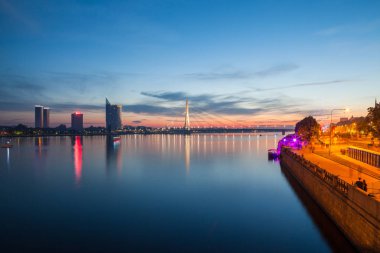 Riga, Letonya Daugava Nehri üzerinde derin günbatımı panoramik sahne. Sağ sol ve eski şehirde yeni iş binaları.