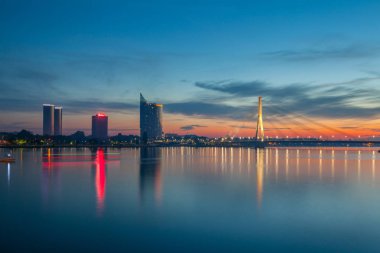 Riga, Letonya Daugava Nehri üzerinde derin günbatımı panoramik sahne. Yeni iş binalar ve Askılı köprü
