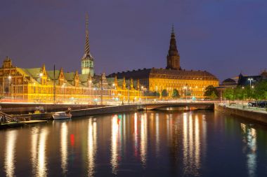 Kopenhag kanal üzerinden Christiansborg Sarayı ve borsa binasında gece görünümü.