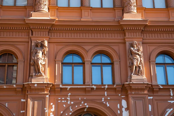 Klasszikus stílusú vörös épület homlokzatán szobraival. Az építészeti részletek. — Stock Fotó