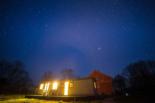 Foto nocturna de pequeña cabina iluminada y cielo estrellado . — Foto de Stock