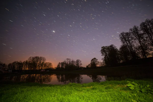 Vue de nuit du ciel étoilé près d'une petite rivière. Premier plan d'herbe en surbrillance . — Photo