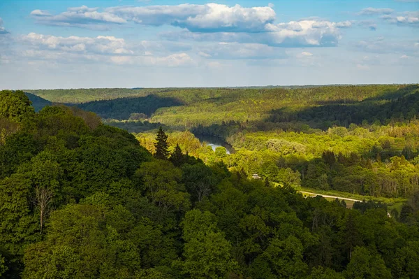 Güzel gökyüzü ve bulutlar yeşil orman, Güneş tarafından kaplı tepeler üzerinde. Gauja Nehri, Letonya.