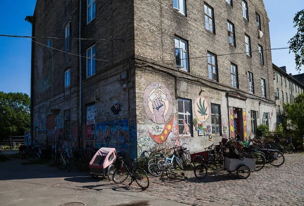 COPENHAGEN, DINAMARCA - 26 JUNIO 2016: Bicicletas antiguas a lo largo de un edificio abandonado con graffiti. Christiania . — Foto de Stock