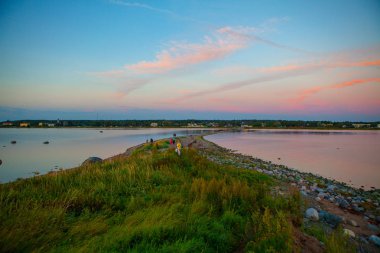 Deniz kenarı yeşil çim büyüyen ile deniz üzerinden günbatımı