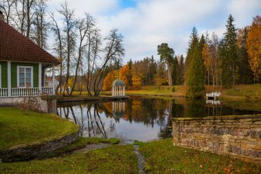 Gölet diğer resindential binaları ile sahilde gazebo (rotunda). Estonya manor. Sonbahar.