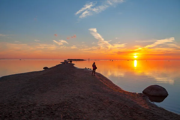 Красочный закат над песчаным побережьем моря. Женщина наслаждается рассветом — стоковое фото