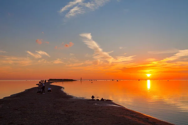 Kleurrijke zonsondergang over zand kust van de zee. Mensen genieten van de dageraad — Stockfoto